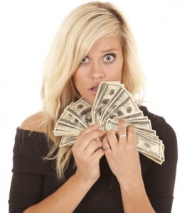 Woman looking at money with shocked expression